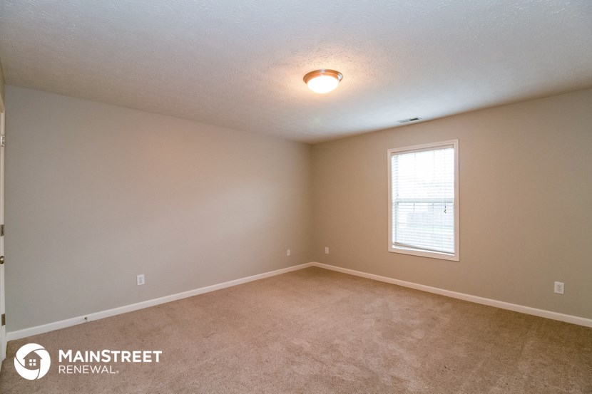 the spacious living room with carpeting and a window