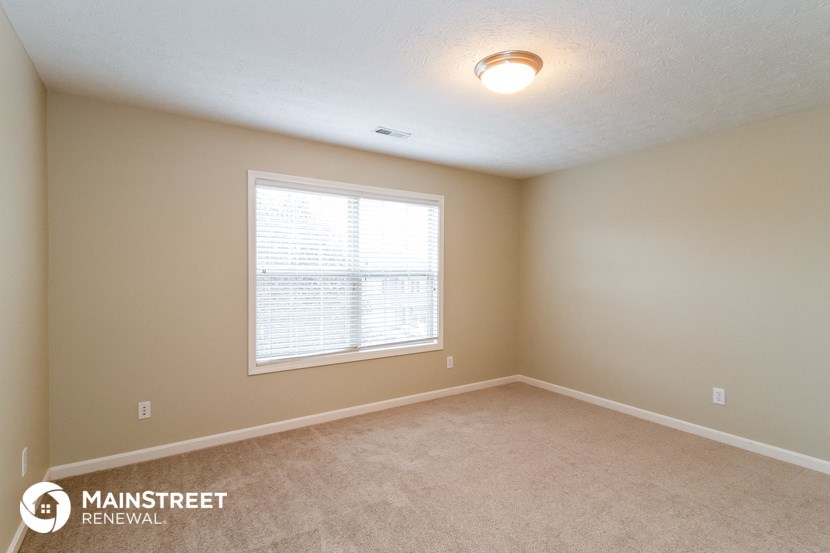 a bedroom with a large window and a carpeted floor