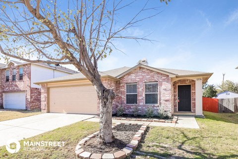 a brick house with a tree in the front yard
