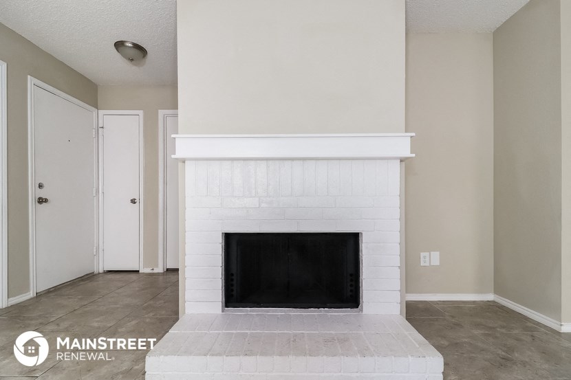 the living room has a white brick fireplace and tile flooring