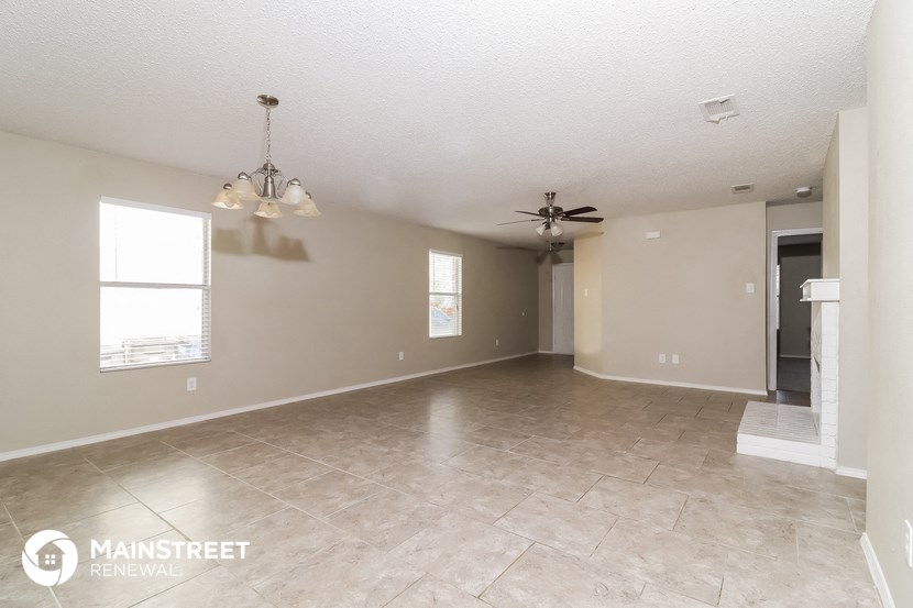 an empty living room with tile flooring and a ceiling fan