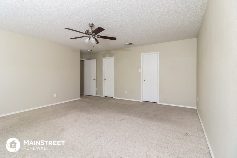 a spacious living room with carpet and a ceiling fan