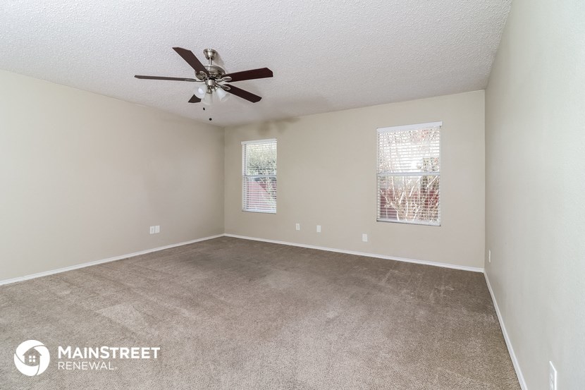 a spacious living room with carpet and a ceiling fan