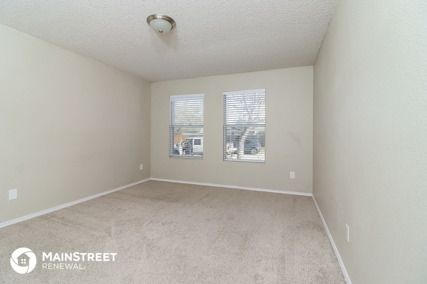 a spacious living room with two windows and a carpeted floor