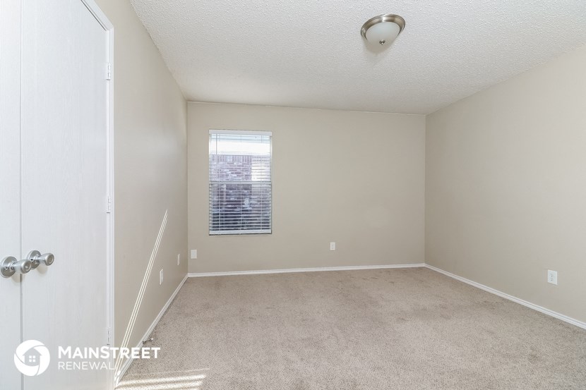 a spacious bedroom with carpeted flooring and a window