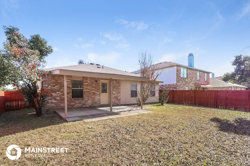 a small brick house with a yard and a red fence