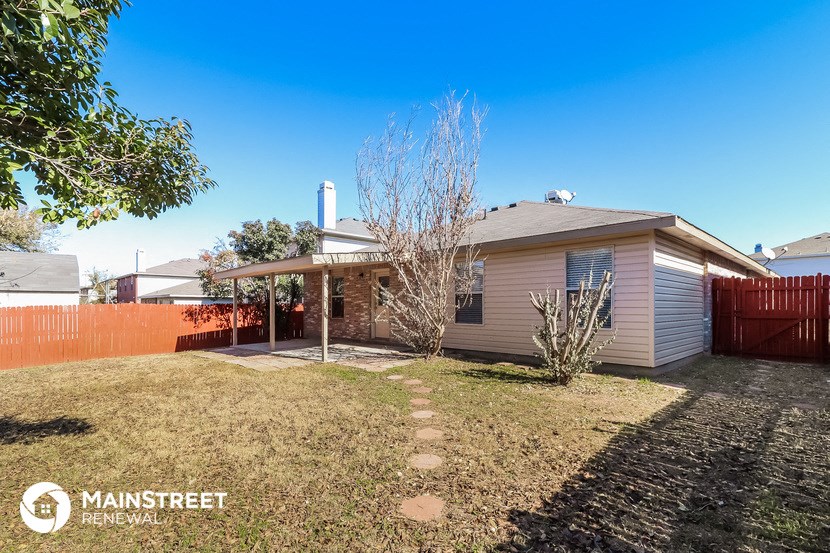 a small house with a yard and a red fence