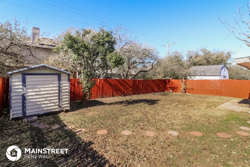 a backyard with a shed and a red fence