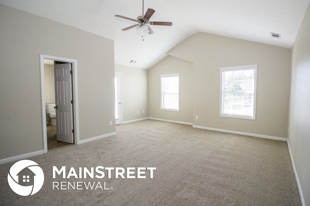 a master bedroom with carpet and a ceiling fan