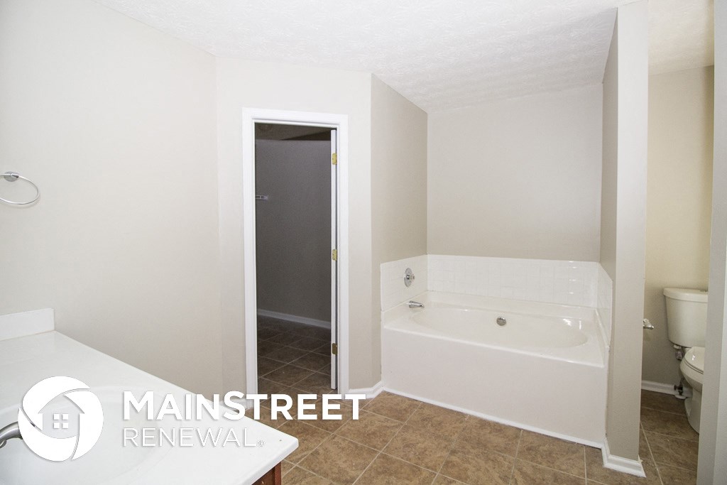 a small bathroom with a tub and a shower and a toilet