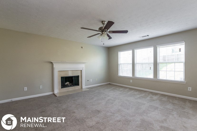 an empty living room with a ceiling fan and a fireplace