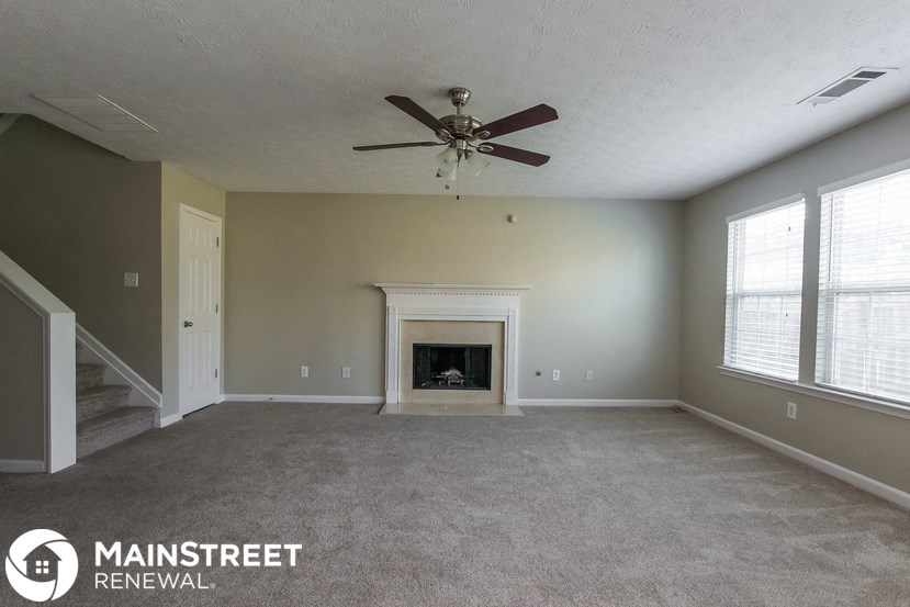 an empty living room with a ceiling fan and a fireplace
