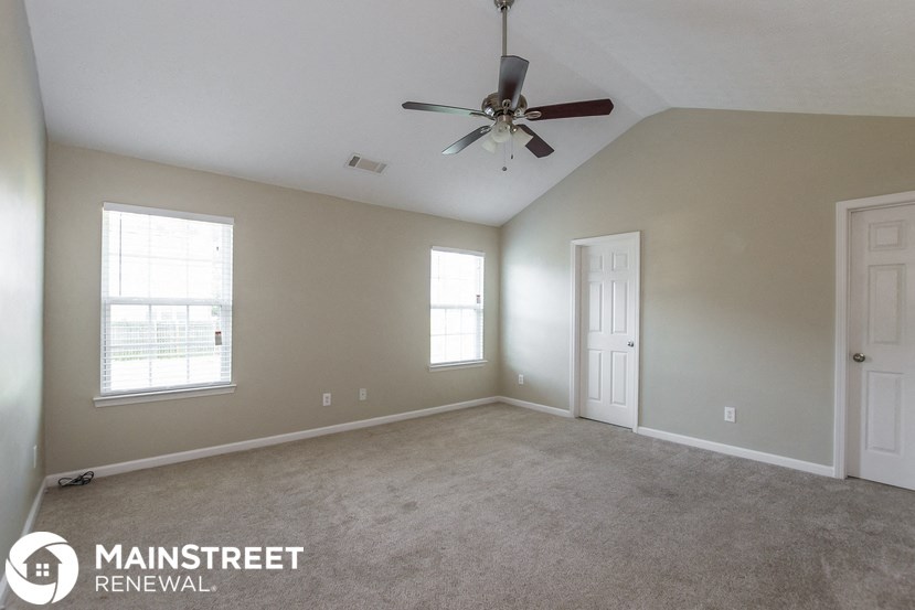 the living room of an empty home with a ceiling fan