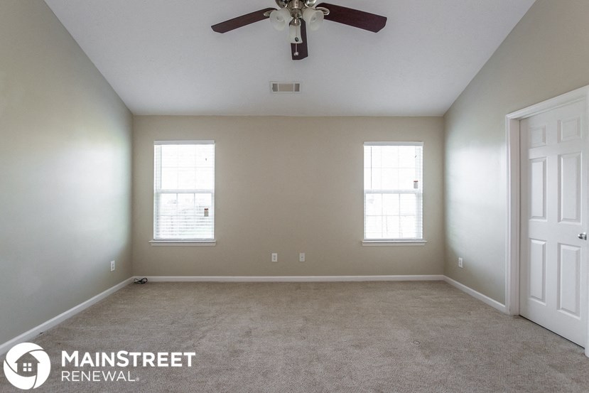 an empty room with a ceiling fan and two windows