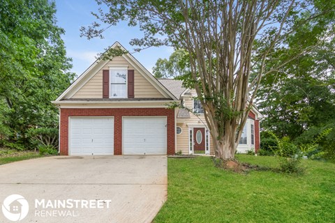 a brick house with two garage doors and a tree