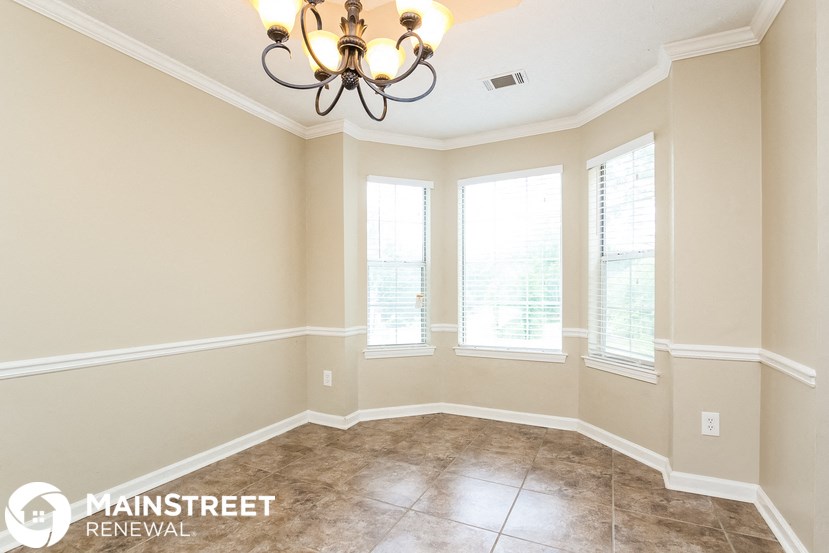 a dining room with a chandelier and three windows