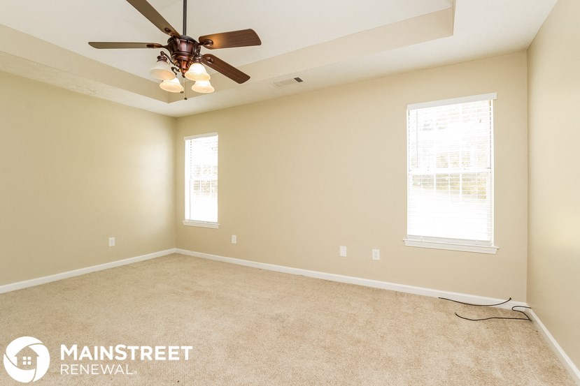 a living room with a ceiling fan and a carpet