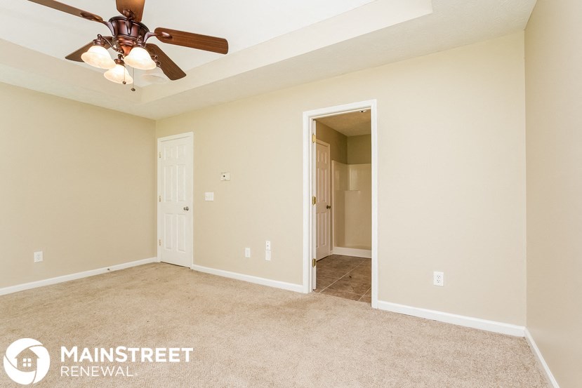 a bedroom with a ceiling fan and a door to a closet