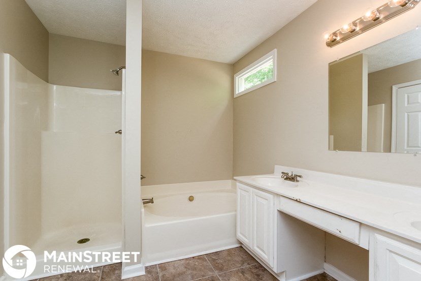 a white bathroom with a tub and a sink and a mirror