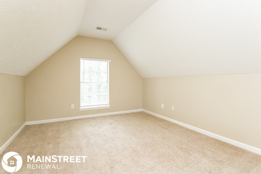 the bedroom of a home with carpet and a window