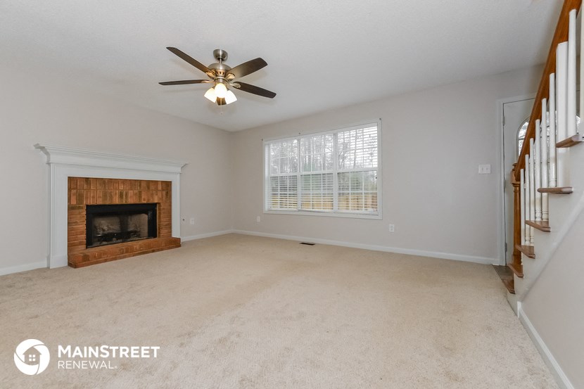 a living room with a fireplace and a ceiling fan