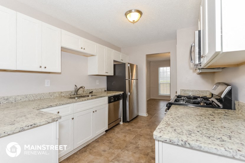 a kitchen with white cabinets and granite counter tops and a stove and refrigerator