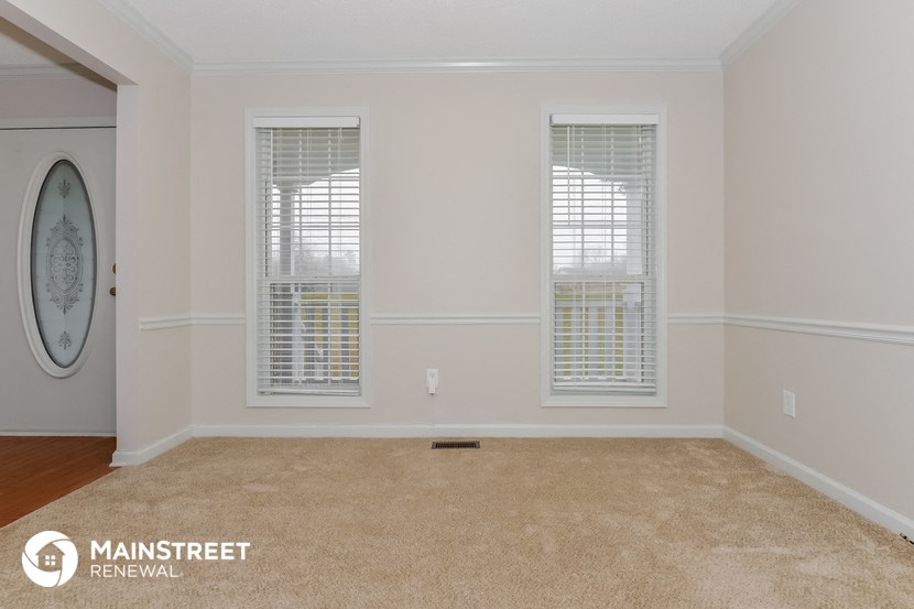 the living room of a home with two windows and a carpet