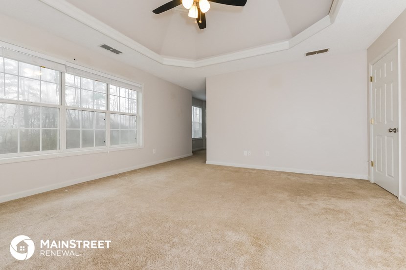 an empty living room with a ceiling fan and a large window