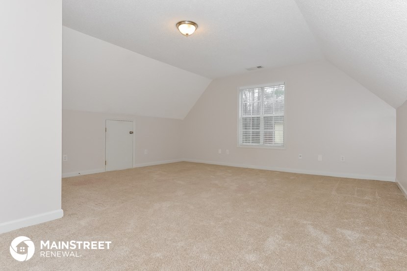 the spacious living room with carpeting and a window