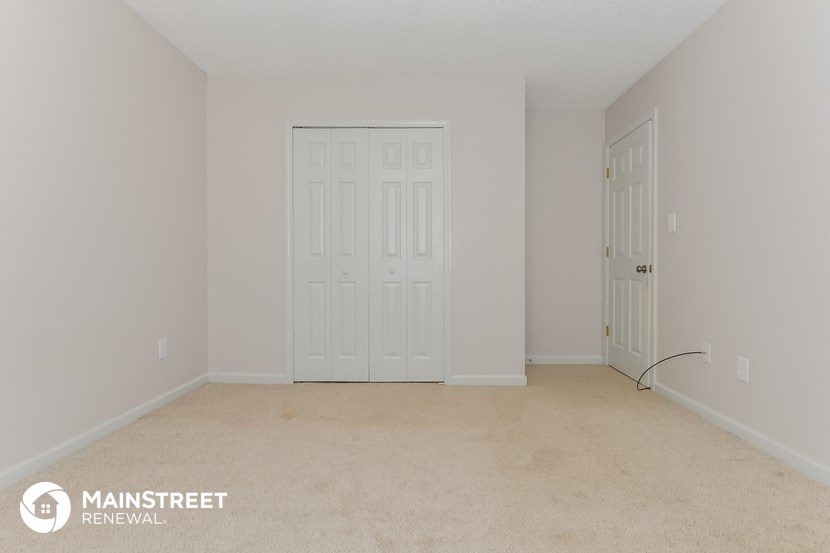 the upstairs bedroom with two closet doors and a carpeted floor