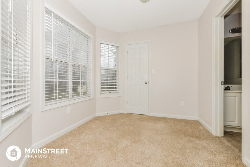 a spacious living room with a white door and window