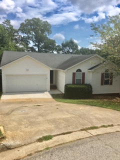 a white house with a driveway and a tree