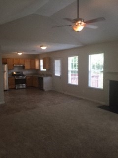 an empty living room and kitchen with a ceiling fan