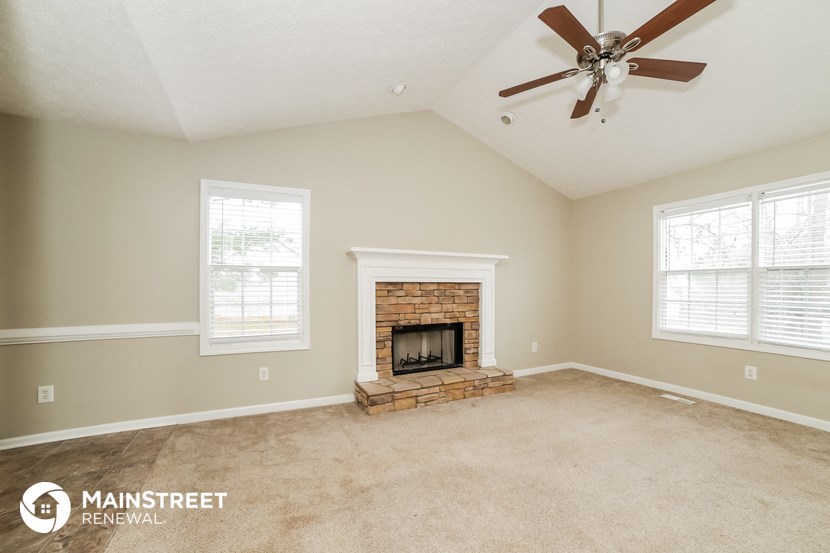 the living room has a brick fireplace and a ceiling fan