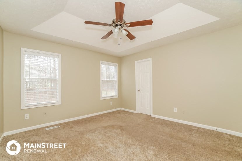 the master bedroom has a carpeted floor and a ceiling fan