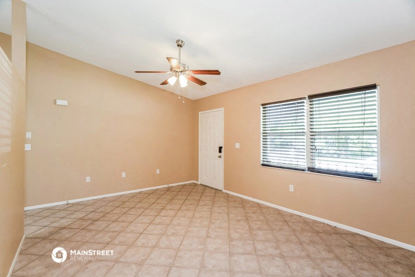 an empty living room with a ceiling fan and a window