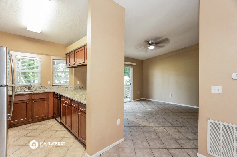 an empty kitchen and living room with a ceiling fan