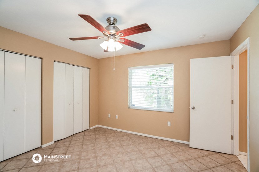 the living room has a ceiling fan and a tiled floor