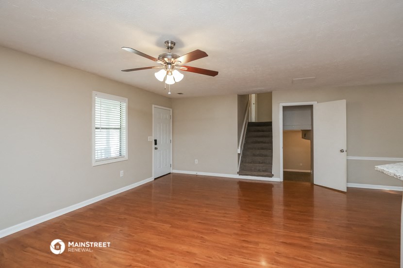 an empty living room with wood floors and a ceiling fan