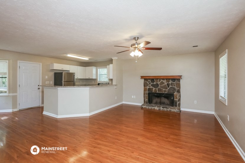 an empty living room with a fireplace and a ceiling fan