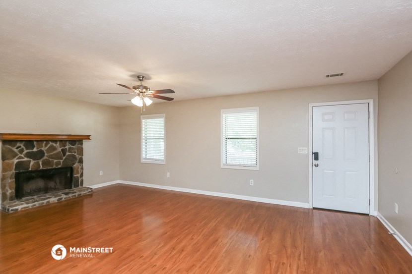 an empty living room with a fireplace and a ceiling fan