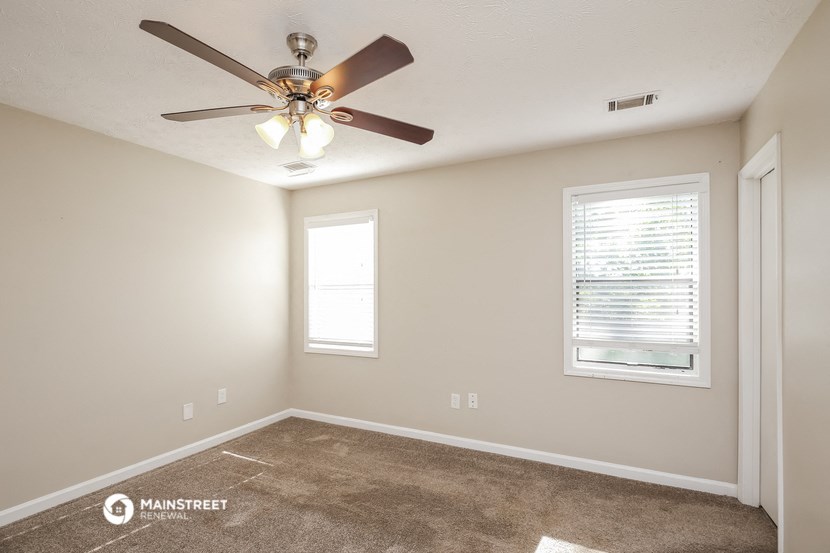 the spacious living room with ceiling fan and carpet