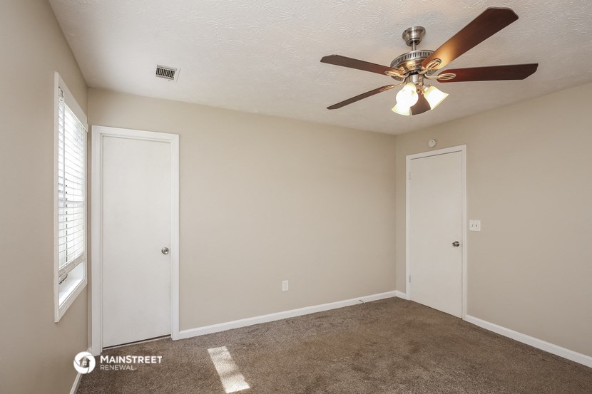 the spacious living room with ceiling fan and window
