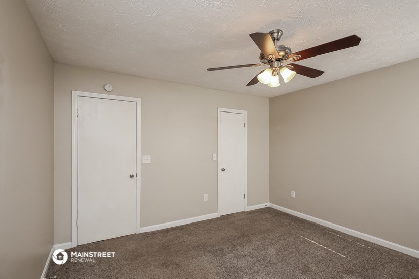 a empty living room with a ceiling fan and a closet