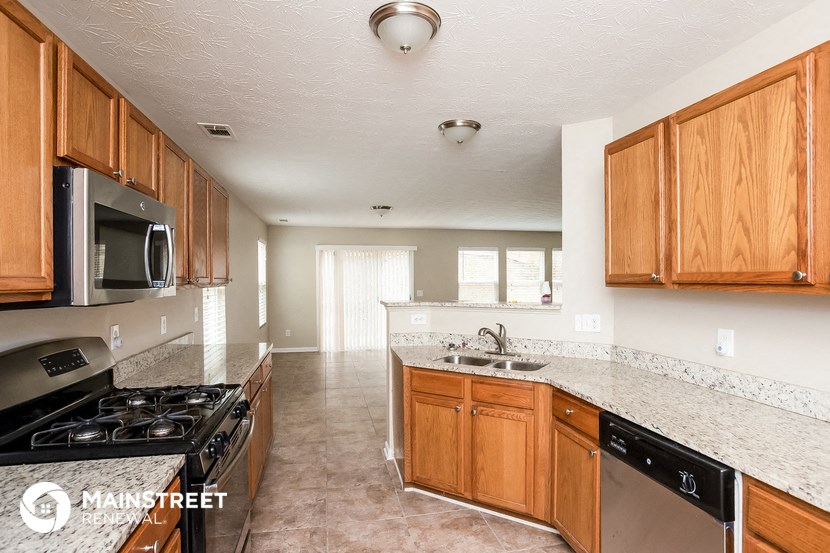 a kitchen with wood cabinets and granite counter tops and a stove and microwave