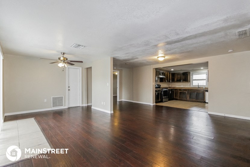 the living room and kitchen of an empty house with wood floors and a ceiling fan