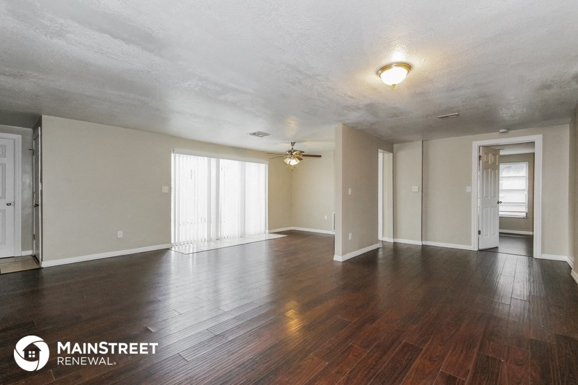 an empty living room with wood floors and a ceiling fan