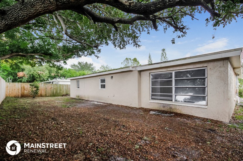 a small house with a yard and a tree in front of it