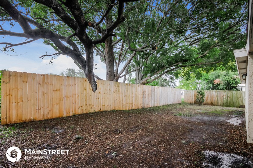 a fenced in backyard with a tree and a wooden fence