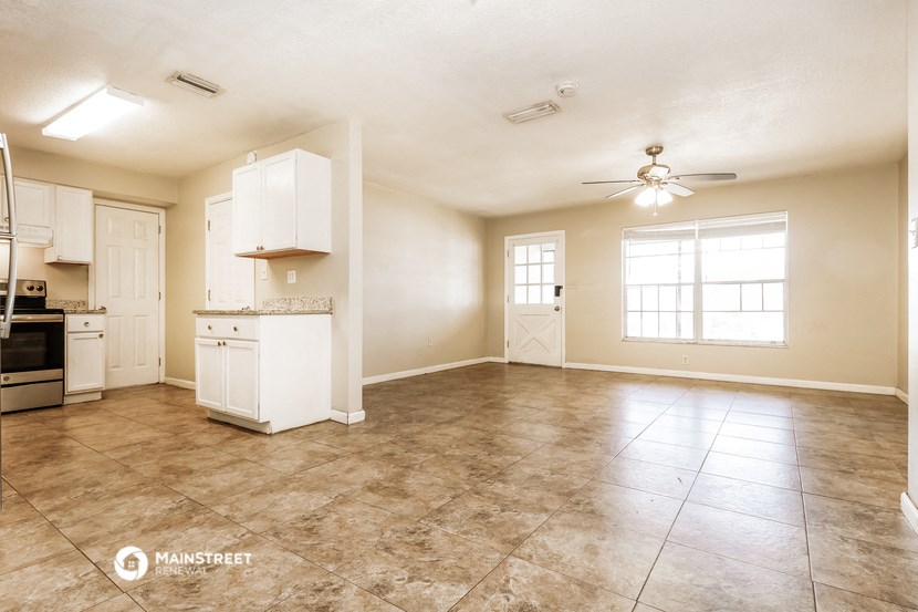 an empty kitchen and living room with a ceiling fan